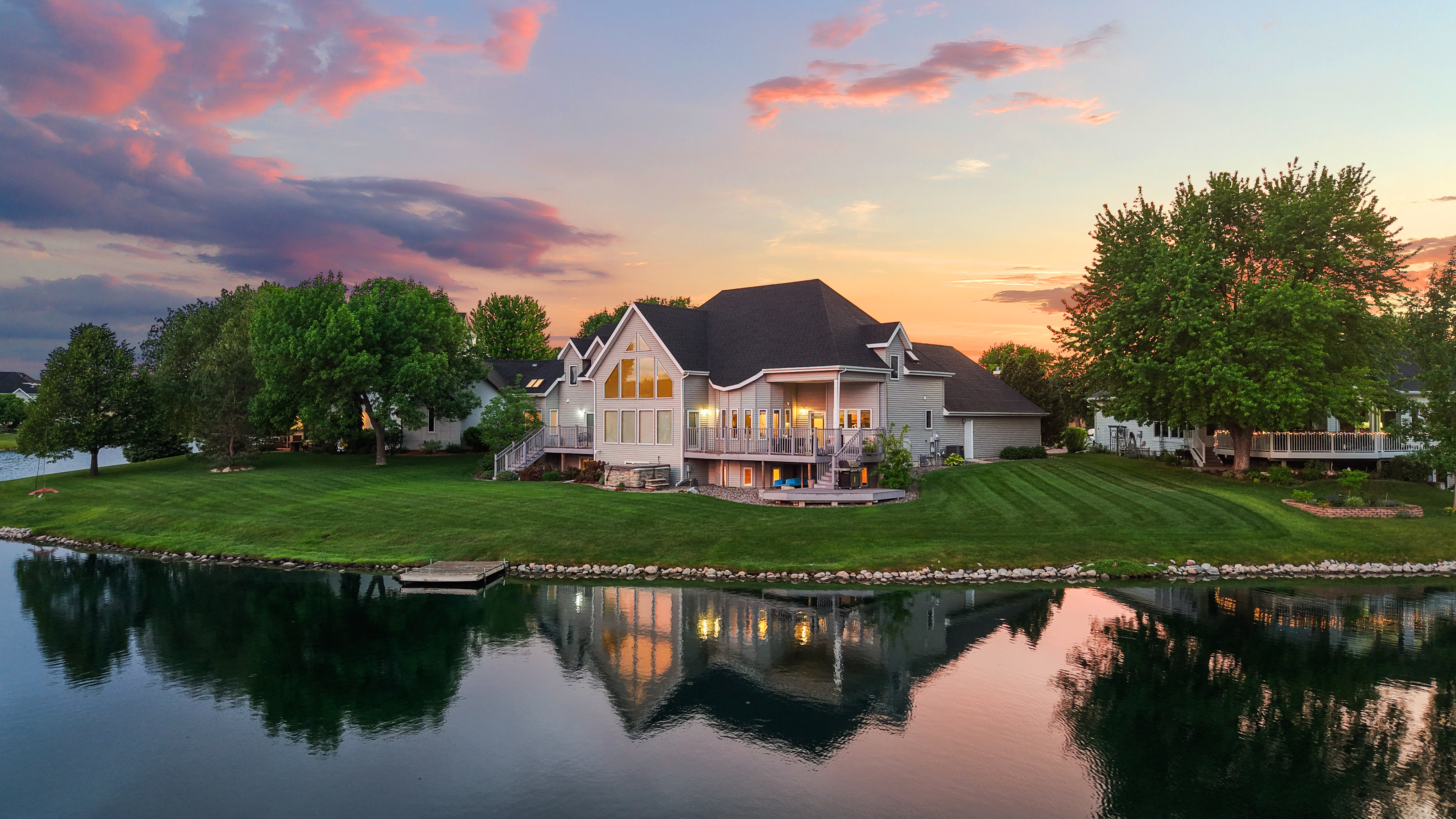 Twilight exterior photo of a lakefront home with interior lights on